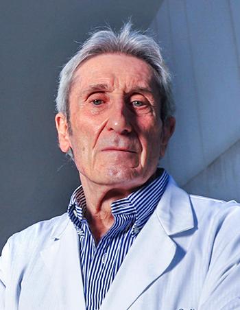 Es la foto de perfil de un pediatra en Huixquilucan de Hospital Angeles Lomas. Usa una bata blanca, camisa azul con rayas blancas, tiene ojos azules y es canoso.