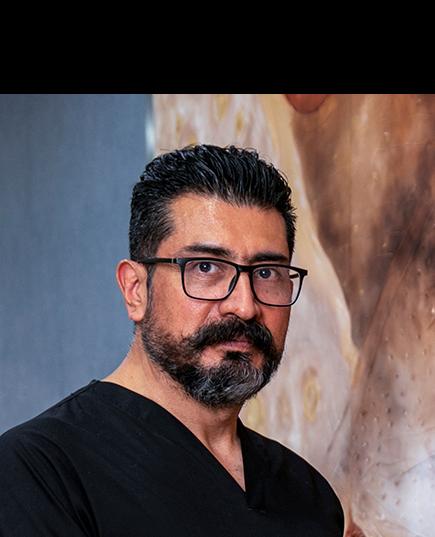 Es la foto de perfil de un internista en León de Hospital Angeles León. Usa un uniforme negro, tiene lentes cuadrados y de fondo está una imagen de color café amarillo claro con azul.