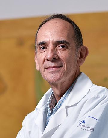 Es la foto de perfil de un cirujano general en Villahermosa de Hospital Angeles. Usa una bata blanca. Tiene el cabello negro. Está sonriendo ligeramente.